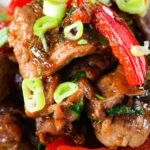 Close-up spicy Thai basil and beef stir fry served with jasmine rice and spring onions.