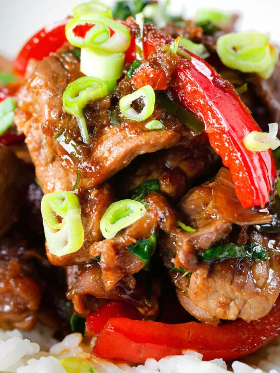Close-up spicy Thai basil and beef stir fry served with jasmine rice and spring onions.