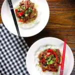 Overhead spicy Thai basil and beef stir fry served with jasmine rice and spring onions.