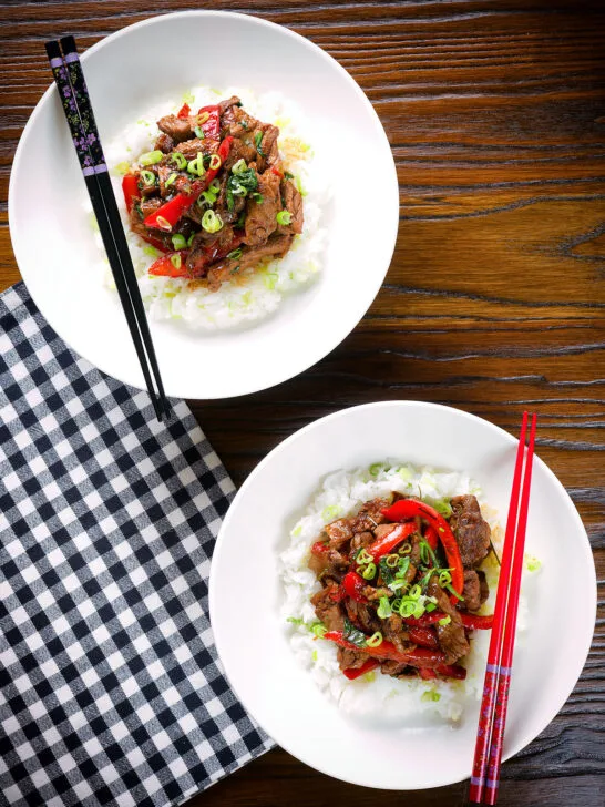 Overhead spicy Thai basil and beef stir fry served with jasmine rice and spring onions.