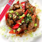 Close-up overhead spicy Thai basil and beef stir fry served with jasmine rice and spring onions.