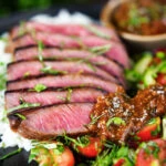 Thai Crying Tiger Steak (Suea Rong Hai) with a spicy dipping sauce, rice, and tomato and cucumber salad.