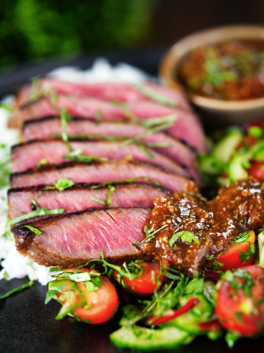 Thai Crying Tiger Steak (Suea Rong Hai) with a spicy dipping sauce, rice, and tomato and cucumber salad.