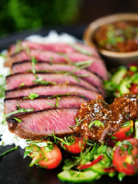 Thai Crying Tiger Steak (Suea Rong Hai) with a spicy dipping sauce, rice, and tomato and cucumber salad.