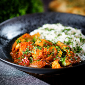 Vegan and vegetarian vegetable rogan josh curry with rice, naan and fresh coriander.