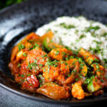 Vegan vegetable rogan josh curry with rice, naan and fresh coriander.