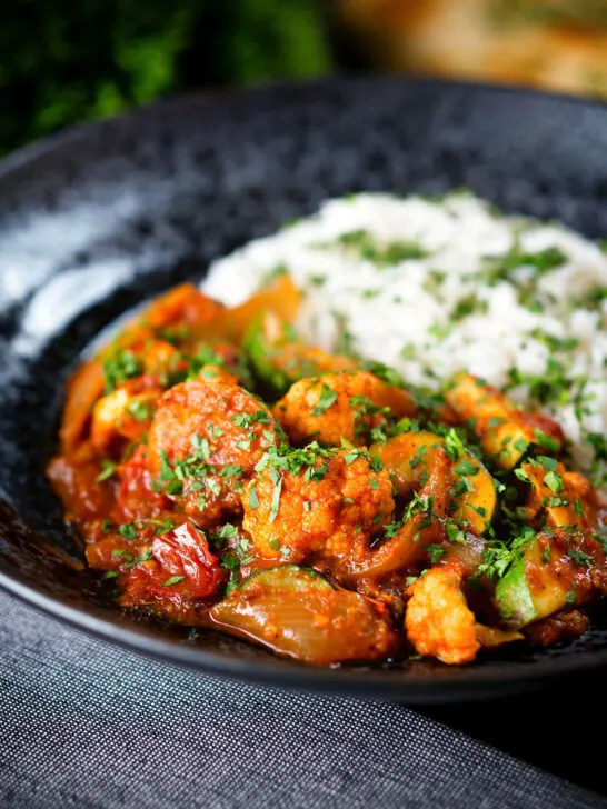Vegan vegetable rogan josh curry with rice, naan and fresh coriander.