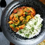 Overhead vegan vegetable rogan josh curry with rice, naan and fresh coriander.