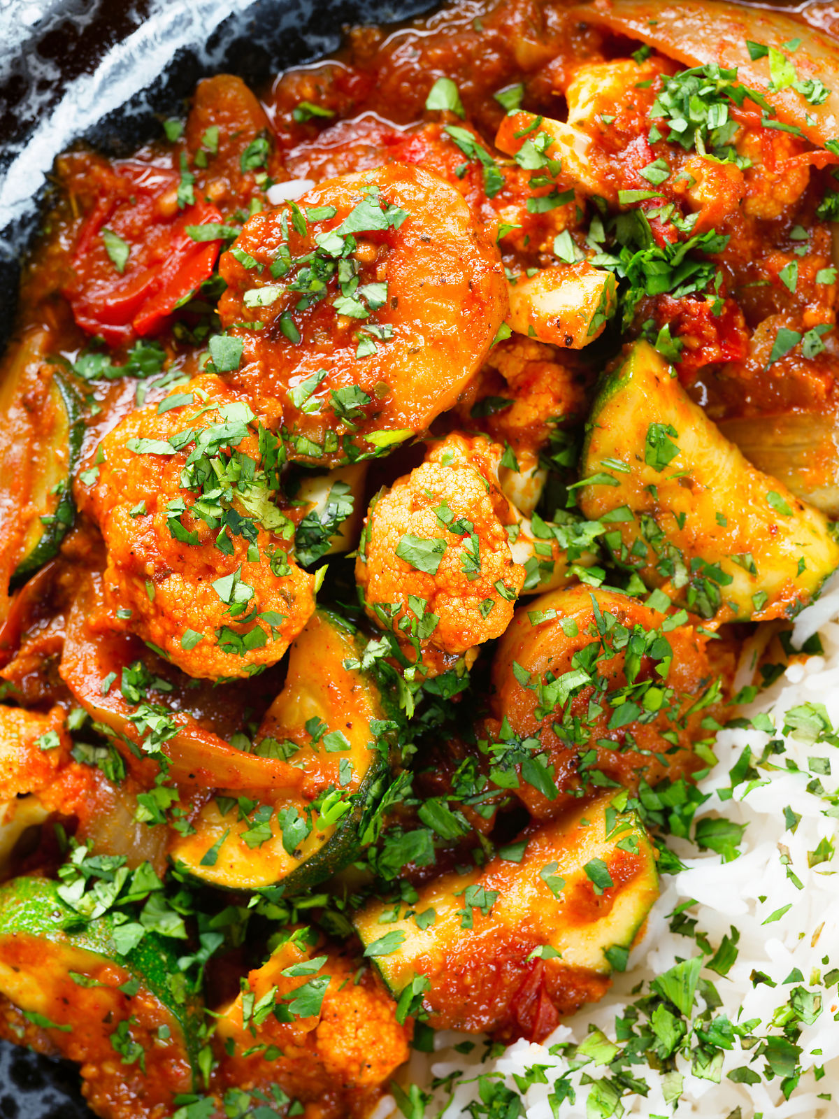Close-up overhead vegan vegetable rogan josh curry with rice and fresh coriander.