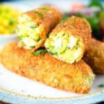 Crispy vegetarian Glamorgan sausages cut open to show the filling.