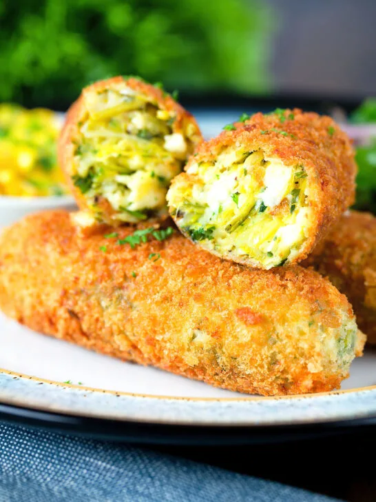 Close-up crispy vegetarian Glamorgan sausages cut open to show the filling.