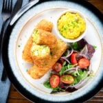 Overhead vegetarian Glamorgan sausages cut open to show the filling served with piccalilli.