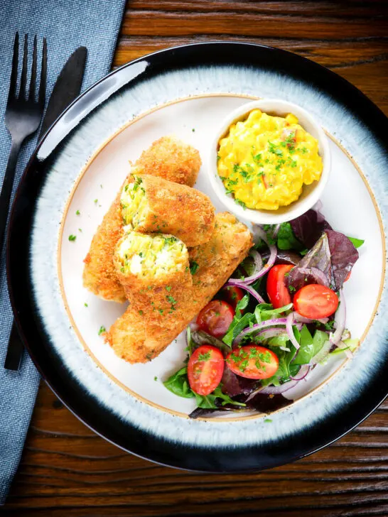 Overhead vegetarian Glamorgan sausages cut open to show the filling served with piccalilli.