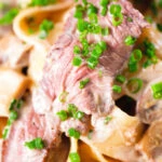 Close-up creamy steak and mushroom pasta (pappardelle) with a "Diane" sauce and snipped chives.