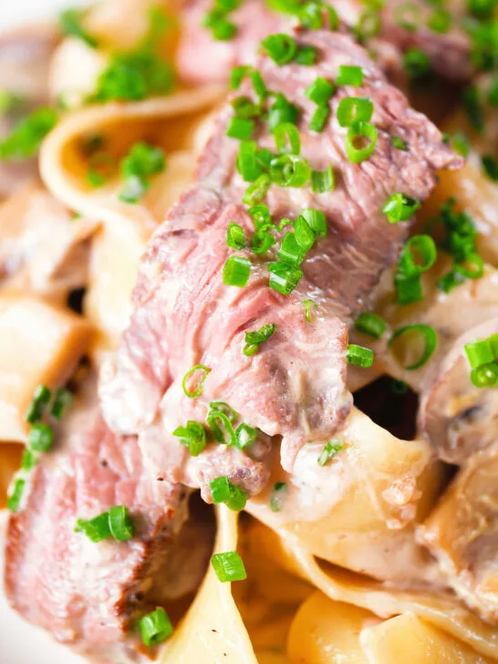 Close-up creamy steak and mushroom pasta (pappardelle) with a "Diane" sauce and snipped chives.