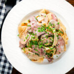 Overhead creamy steak and mushroom pasta (pappardelle) with a "Diane" sauce and snipped chives.