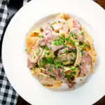 Overhead creamy steak and mushroom pasta (pappardelle) with a "Diane" sauce and snipped chives.