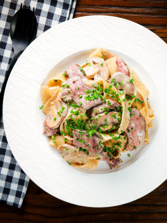 Overhead creamy steak and mushroom pasta (pappardelle) with a "Diane" sauce and snipped chives.