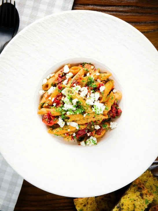 Overhead rose harissa, sun-dried tomato, pepper and feta cheese pasta.