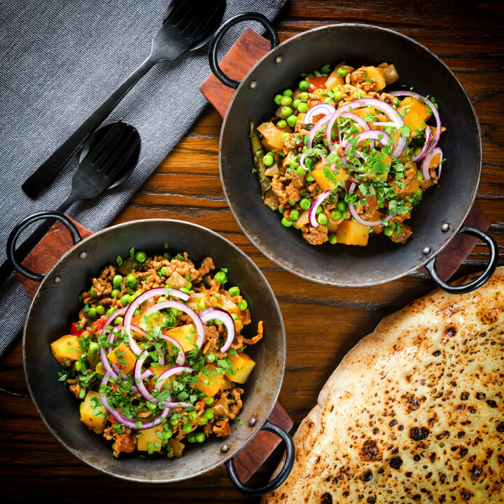 Minced beef, potato and pea curry (aloo keema matar) with naan bread, red onion and coriander.
