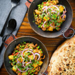 Overhead minced beef, potato and pea curry (aloo keema matar) served with naan bread.