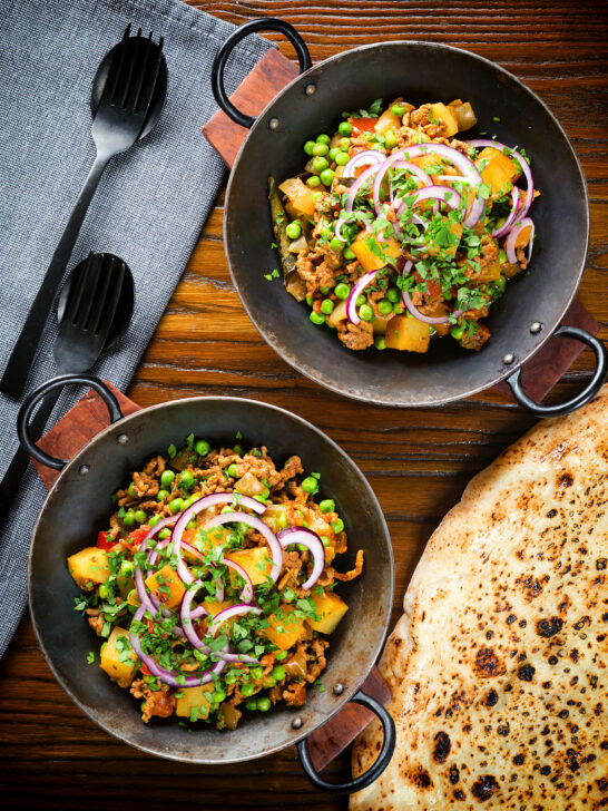 Overhead minced beef, potato and pea curry (aloo keema matar) served with naan bread.