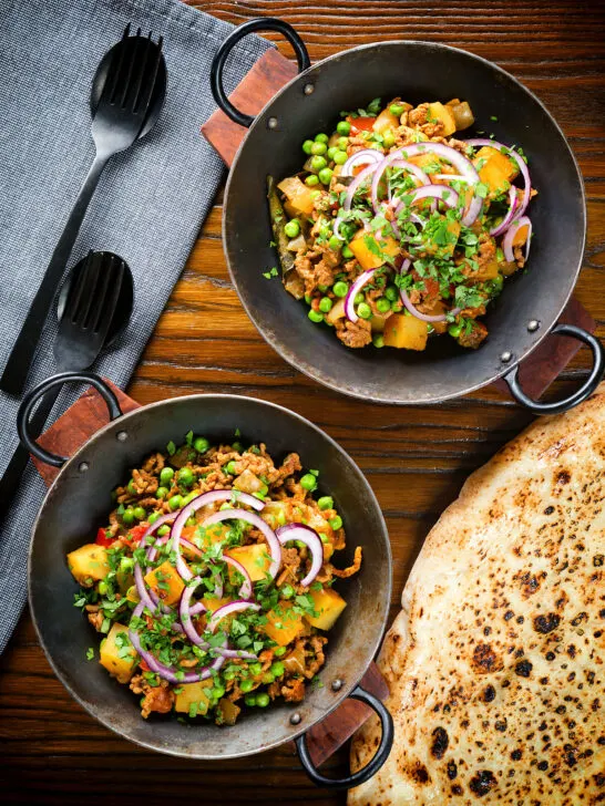 Overhead minced beef, potato and pea curry (aloo keema matar) served with naan bread.