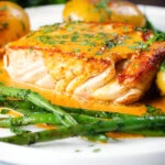 Close-up fried halibut with Thai yellow curry sauce, potatoes, green beans and coriander.