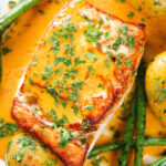 Close-up overhead fried halibut with Thai yellow curry sauce, potatoes, green beans and coriander.