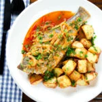 Overhead bourdeto, whole sea bass stew in a paprika broth with crispy potatoes.