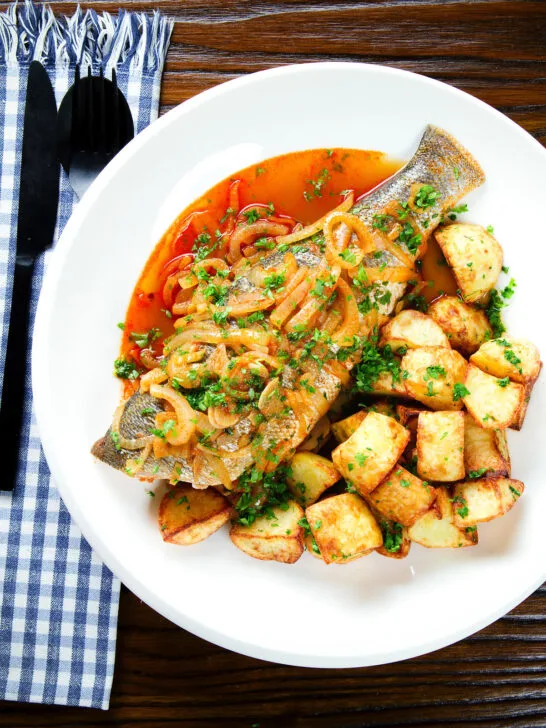 Overhead bourdeto, whole sea bass stew in a paprika broth with crispy potatoes.
