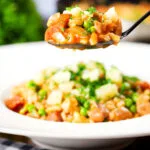 Overhead chicken and chorizo risotto with peas, Manchego cheese on a spoon.