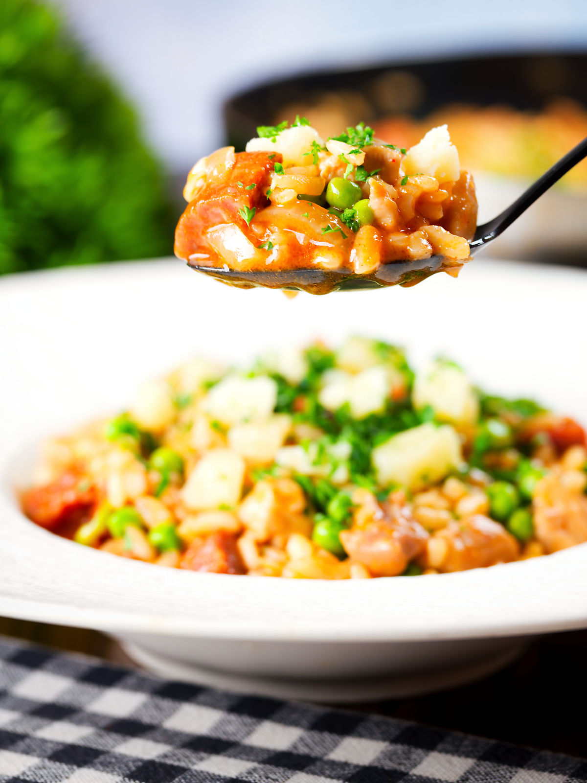 Overhead chicken and chorizo risotto with peas, Manchego cheese on a spoon.
