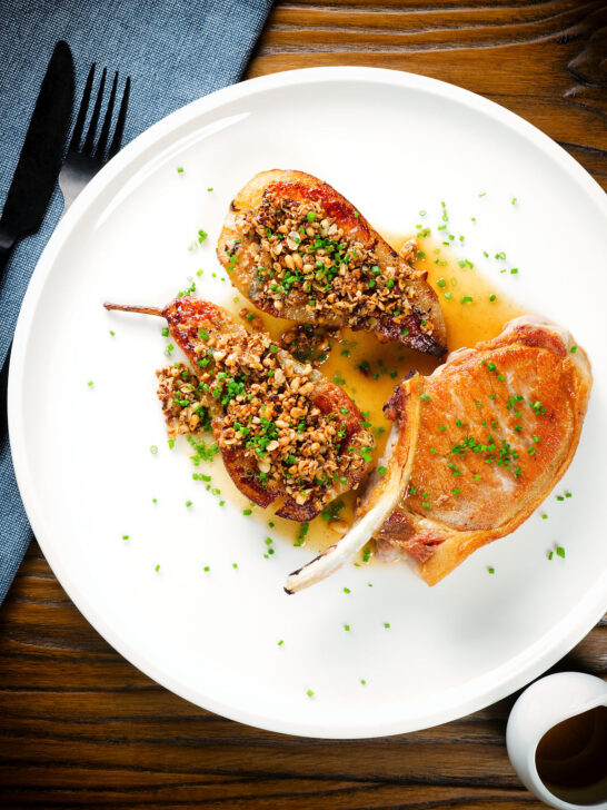 Overhead blue cheese roasted pears with a nutty crumble and cider sauce served with a pork chop.