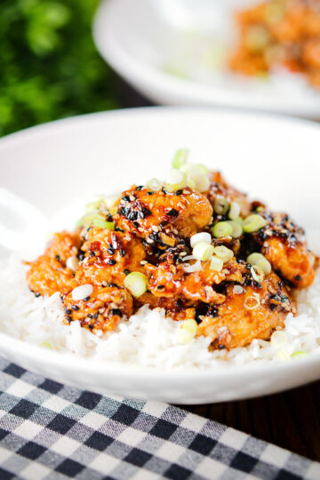 Crispy sticky sesame chicken served with white rice and spring onions.