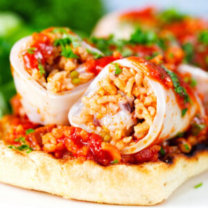 Baked chorizo and brown rice stuffed squid in tomato sauce, served on focaccia with a side salad.