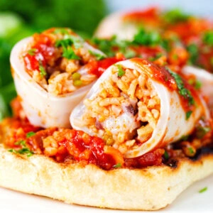 Baked chorizo and brown rice stuffed squid in tomato sauce, served on focaccia with a side salad.