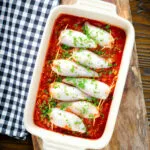 Overhead baked chorizo and brown rice stuffed squid in tomato sauce in a baking dish.
