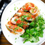 Overhead baked chorizo and brown rice stuffed squid in tomato sauce, served on focaccia.
