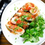 Overhead baked chorizo and brown rice stuffed squid in tomato sauce, served on focaccia.