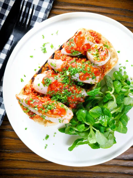 Overhead baked chorizo and brown rice stuffed squid in tomato sauce, served on focaccia.