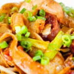Close-up char kway teow (flat rice noodle stir fry) with Chinese sausage and prawns.
