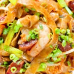 Close-up overhead char kway teow (flat rice noodle stir fry) with Chinese sausage and prawns.
