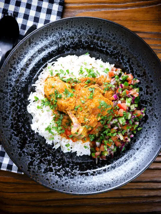 Overhead pakistani chicken salan curry with plain rice and kachumber salad.