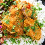 Overhead close-up Pakistani chicken salan curry with plain rice and kachumber salad.