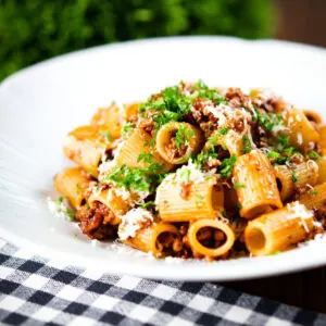 Pork mince pasta ragu with balsamic vinegar, sun-dried tomatoes and sage garnished with parmesan and parsley.