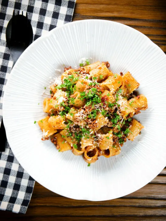 Overhead pork mince pasta ragu with balsamic vinegar, sun-dried tomatoes and sage.