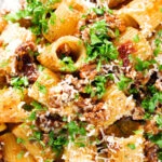 Overhead close-up pork mince pasta ragu with balsamic vinegar, sun-dried tomatoes and sage.
