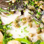 Overhead close-up whole roast turbot with capers, new potatoes and summer greens.