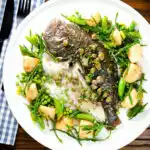 Overhead whole roast turbot with capers, new potatoes, samphire, asparagus, sugar snap peas and garden peas.